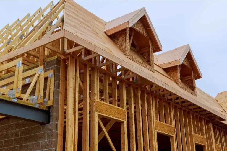 Residential home addition under construction by professional contractors, featuring incomplete roof sheathing and an open wood frame structure.