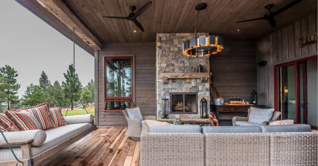 Luxurious covered patio with stone fireplace featuring wooden ceiling, comfortable seating, and mountain views