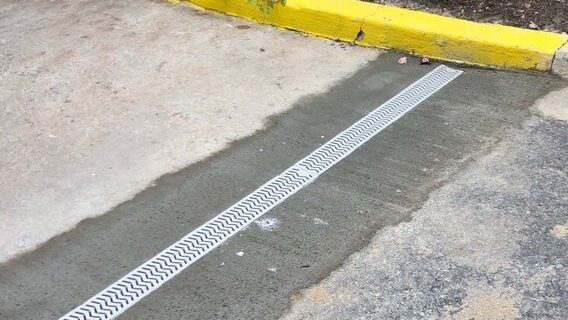 Channel drain installed in pavement to capture surface water and prevent pooling, suitable for commercial or residential use.