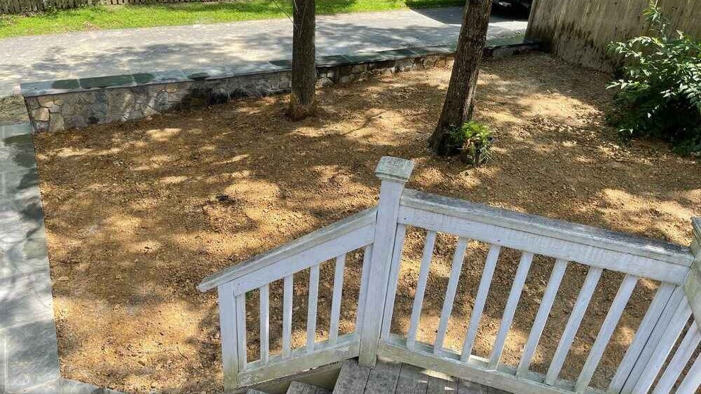 Backyard with newly done regrade sloping soil toward a box drain before grass grows back.