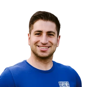 Smiling person wearing a blue shirt against a black background.