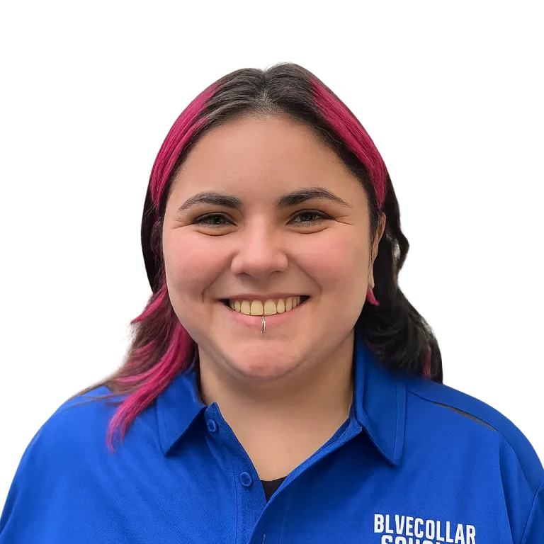 Lucia smiles in a blue "Blue Collar Scholar Construction" shirt, with a dark, stylized background.