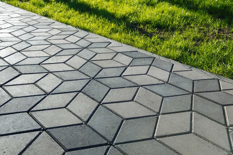 Hexagonal patterned pavement next to green grass.