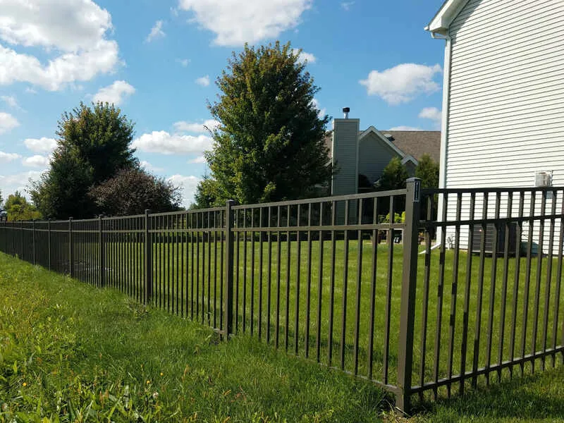 Types of Fences: Aluminum fence enclosing a grassy backyard with trees and a white house.
