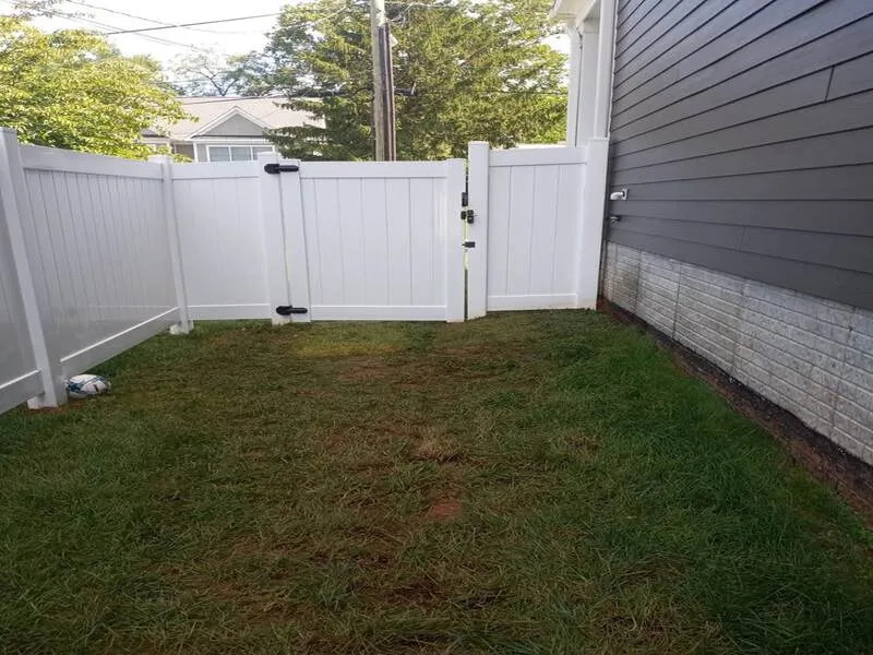 Types of Fences: Small grass yard with white vinyl fence and a soccer ball in the corner.