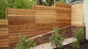 Types of Fences: Wooden fence with stone base and small shrubs in a garden.