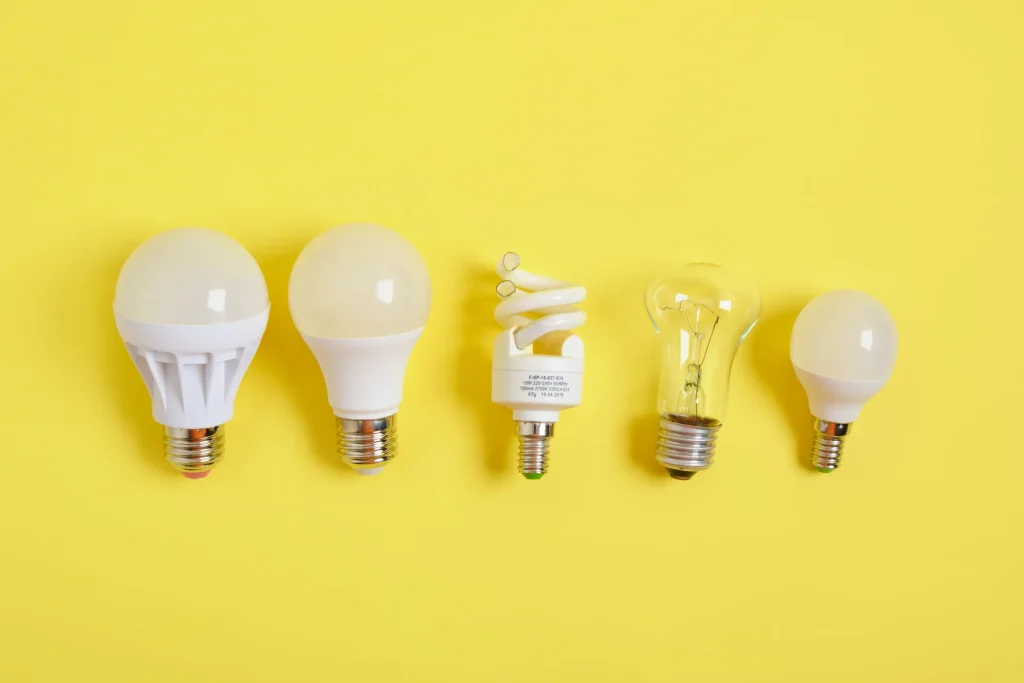 Five different types of light bulbs lined up on a yellow background.