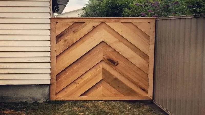 Wooden gate with a chevron pattern between two fences.