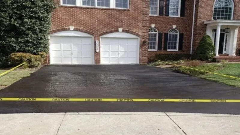 Driveway with fresh asphalt and caution tape blocking entry.