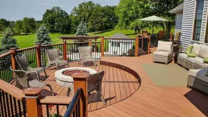Spacious backyard deck material options with a fire pit, wicker chairs, and outdoor seating, overlooking a lush green landscape.
