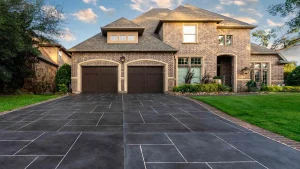 Types of Driveways featuring A brick house with two garage doors and a large tiled driveway.