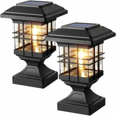 Two black solar-powered lanterns with glowing bulbs inside.
