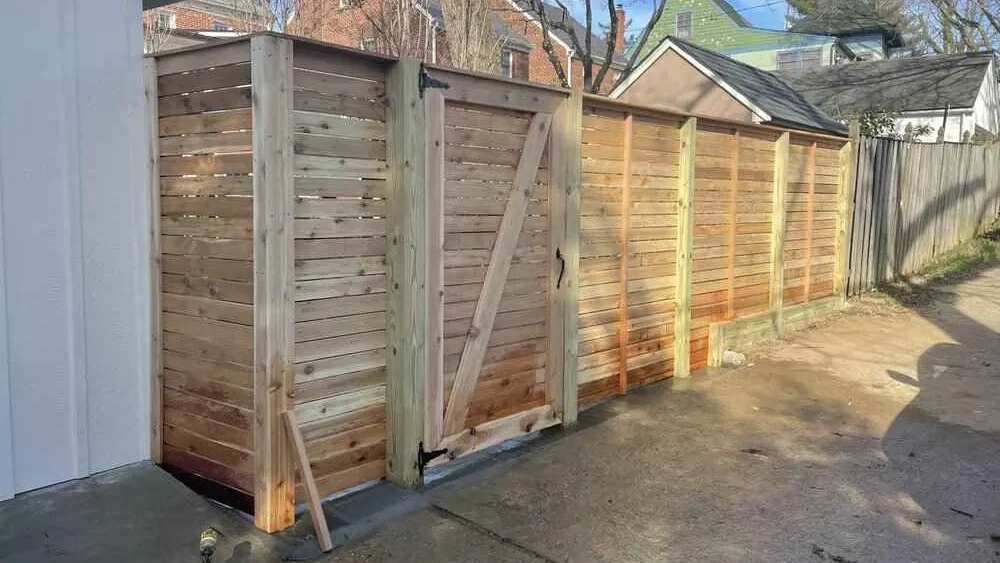 Wooden privacy fence under construction next to a driveway.