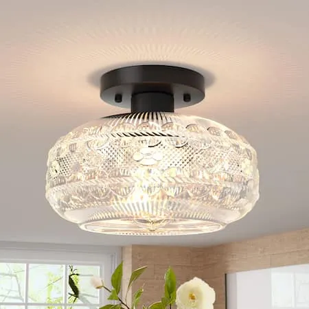 Ceiling light with ornate glass shade, softly illuminating a room.