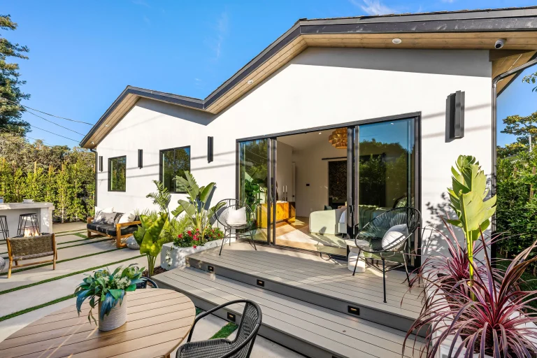Modern patio with seating, plants, and sliding glass doors leading to an interior living space, made by custom home addition contractors.