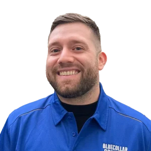 Smiling man in a blue collared shirt.