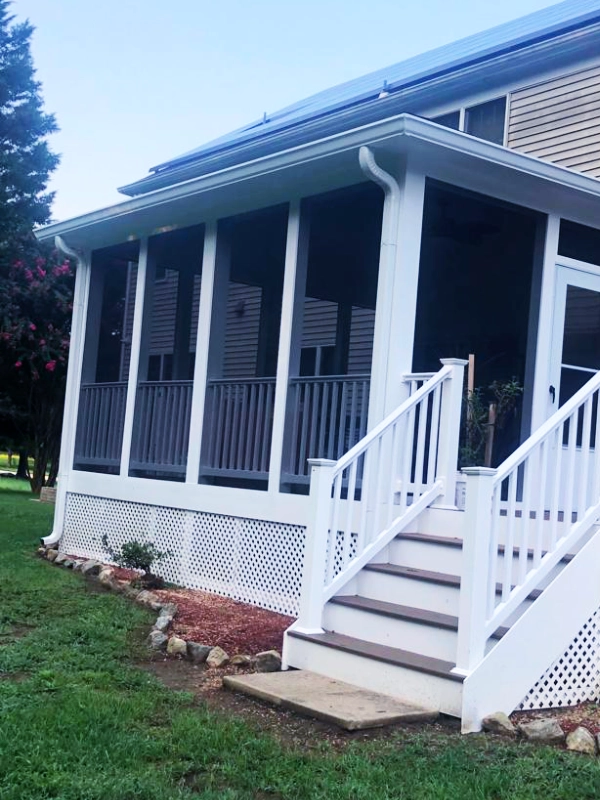 Enclosed bug-free screened-in porch addition with white stairs near a beautiful landscape