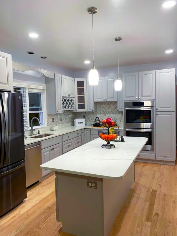 Modern Washington DC kitchen remodel featuring a large marble-top island, light grey cabinetry, and custom herringbone tile backsplash.