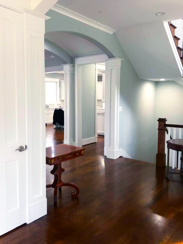 Open-concept Maryland home remodeling showcasing white arched doorways, custom trim work, and dark hardwood floors leading into a bright kitchen.