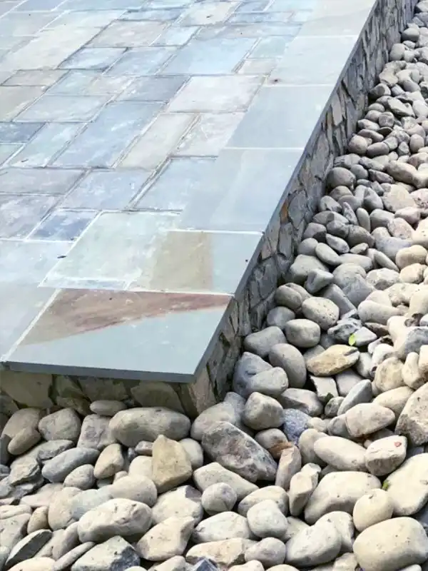 River gravel swale installed behind a sitting wall to prevent flooding in a Maryland home.