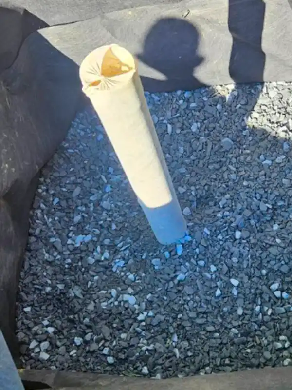 An in-progress dry well installation in the DMV, showing a pit lined with filter fabric and filled with crushed drainage stone.