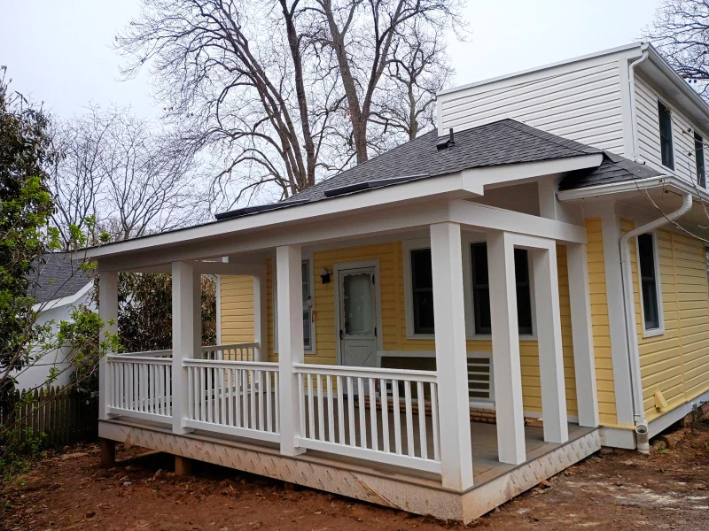 The porch structure nears completion with white composite trim and Trex flooring installed, illustrating the integrated and original look of the addition.