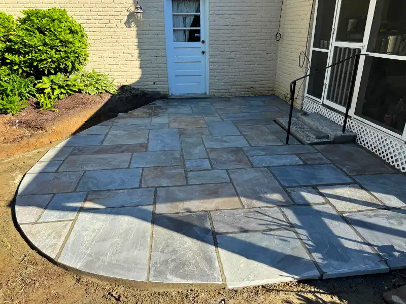 Newly improved natural stone patio with wet flagstone surface showing blended blue-gray and tan tones