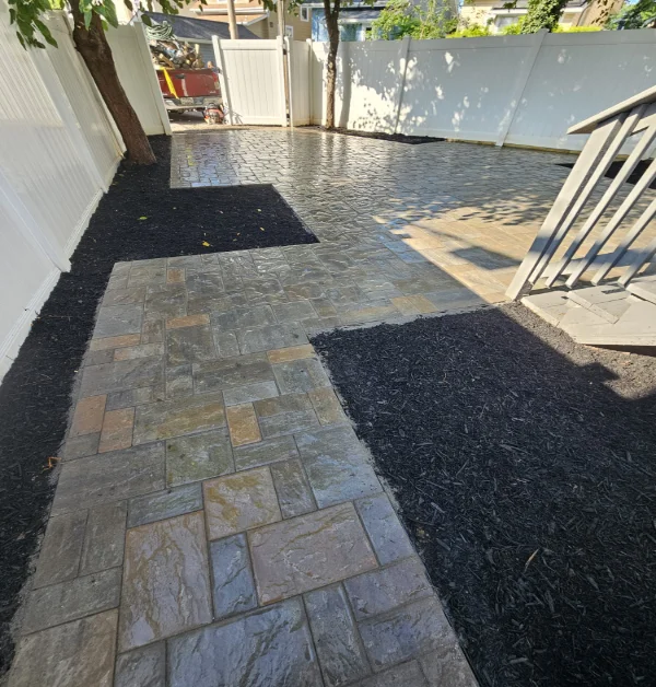 completed backyard transformation of a paver patio with a walkway