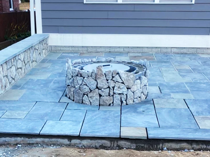 Natural stone veneer being applied to exterior of fire pit structure