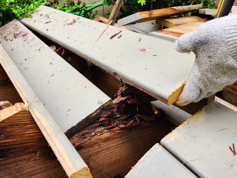 Contractor removing old deck planks to access rotted framing underneath