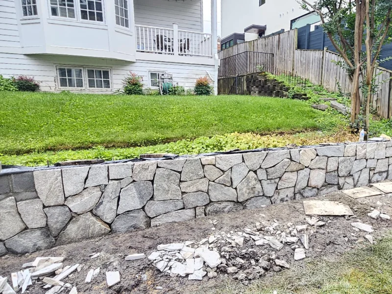 Applying stone veneer to retaining wall during construction