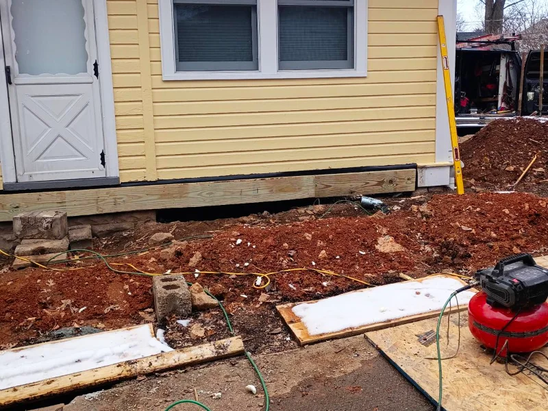 The old deck is removed, and a new pressure-treated ledger board is secured to the house to initiate construction of the new porch.