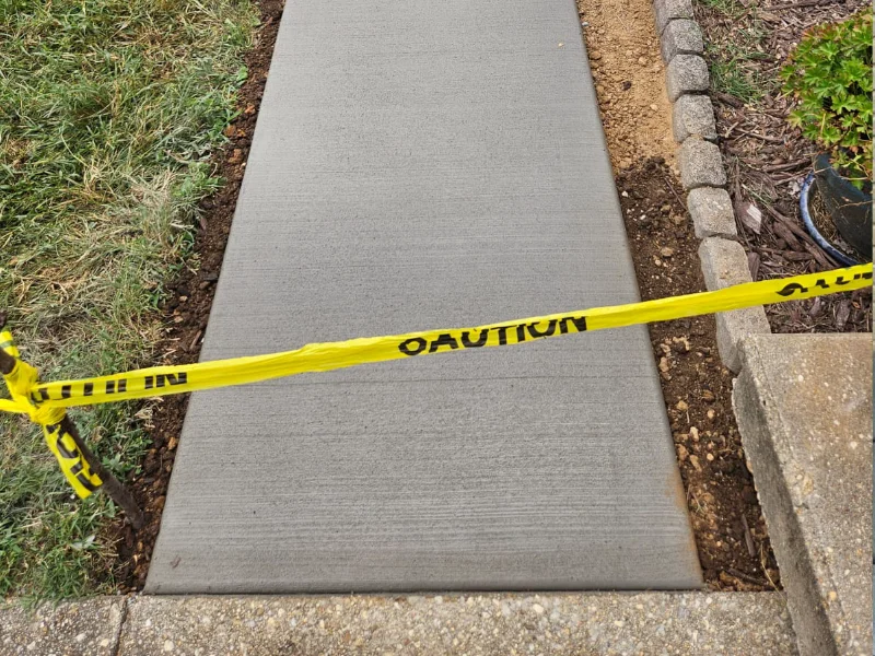Poured concrete walkway during installation with caution tape