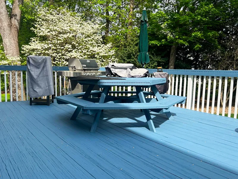 Backyard wood deck after repainting with matching finish on the deck boards, benches, railings, and picnic table.