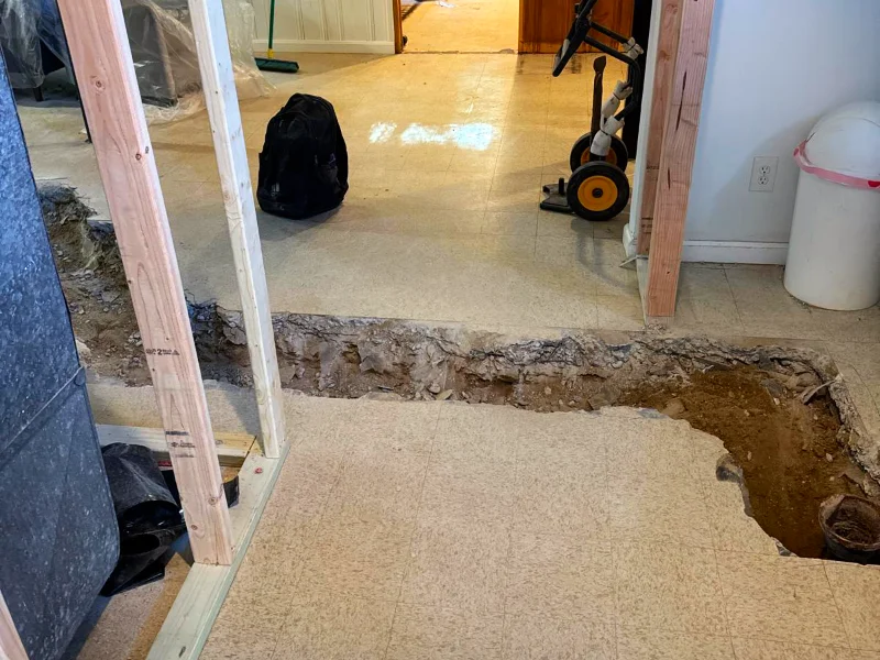 Basement floor opened during construction to install new plumbing and utility lines for the relocated kitchen island sink and dishwasher.