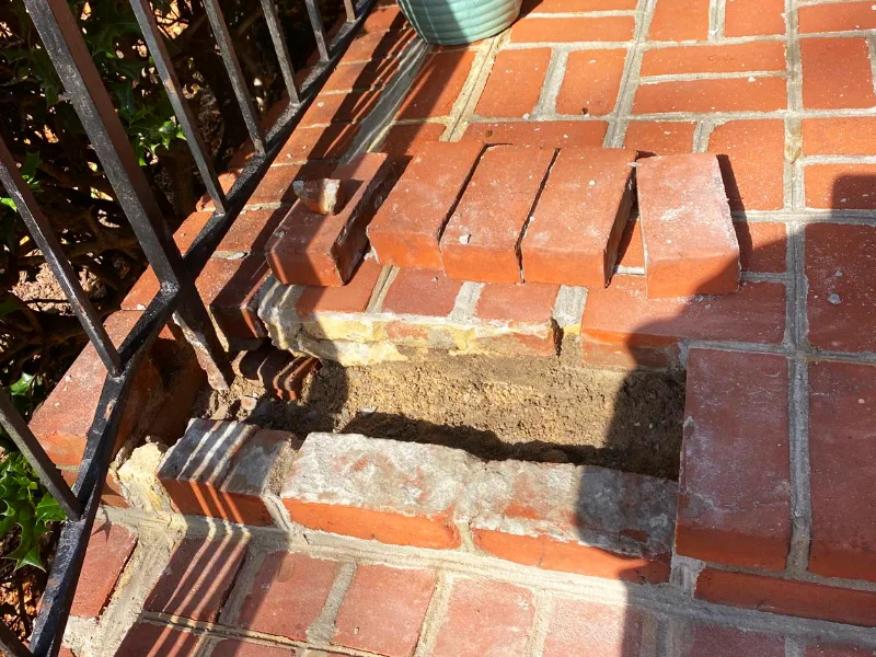 Staircase repair area with damaged bricks removed to prepare for replacement and repointing.
