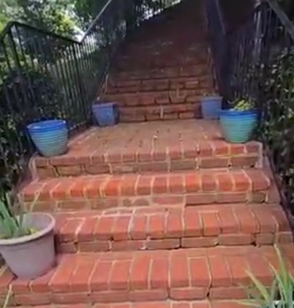 Wide view of the brick staircase before repairs, with visible mortar deterioration across the steps and landings.