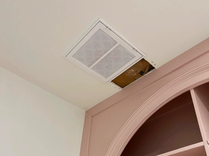 Ceiling finishing work in progress above custom arched built-in cabinetry, with vent installation and trim details being completed before final project closeout.