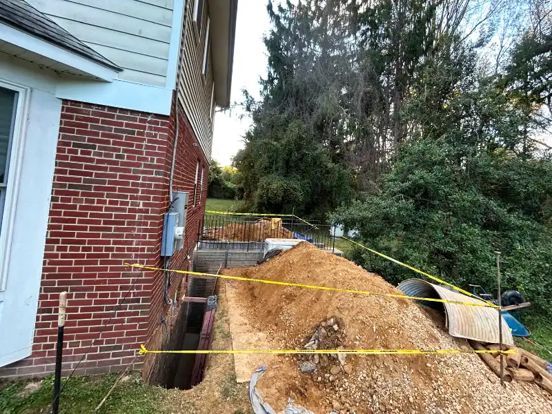 Foundation perimeter being backfilled and graded after waterproofing and drainage installation were completed.