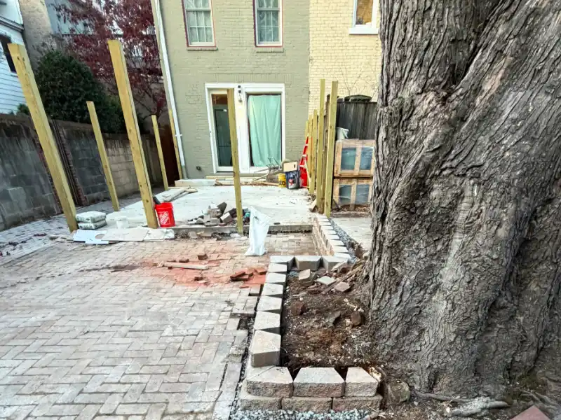 full view of dc property with foundation for patio, fence, and retaining wall