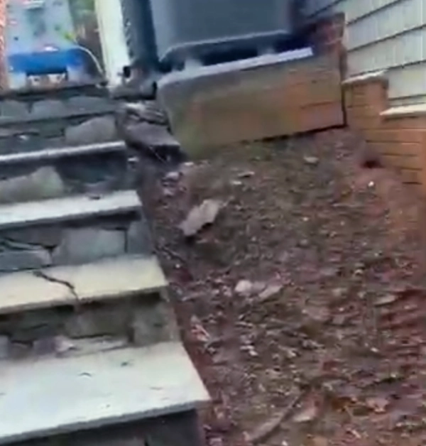 Severe soil erosion is visible beneath a residential HVAC condenser unit prior to stabilization work.