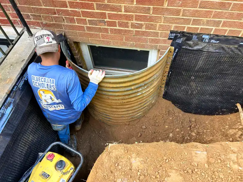 Exterior foundation wall coated with waterproofing material and protected by a drainage membrane before backfilling and final grading.