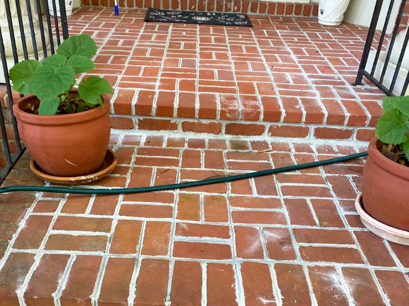 Front entry landing before restoration, showing worn mortar joints between the brick pavers.