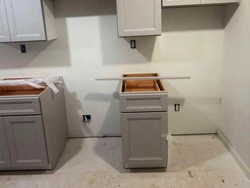 Gray kitchen cabinets installed during construction before countertops, backsplash, and appliances were completed.