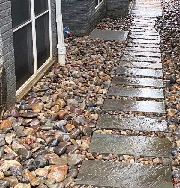 Completed side yard featuring a natural flagstone walkway through a river rock drainage bed leading to a custom cedar double gate in Bethesda, MD.
