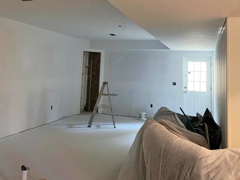 Newly framed and painted hallway leading into the basement in-law suite before final trim, flooring, and fixture installation.
