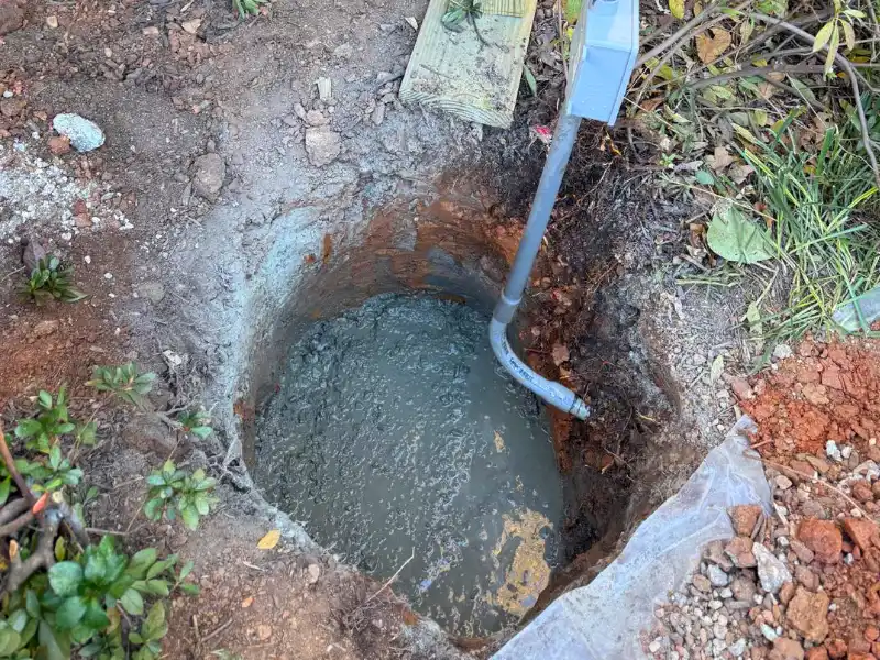 Freshly poured concrete footing beneath the porch ready for installation of a new pressure-treated support post.