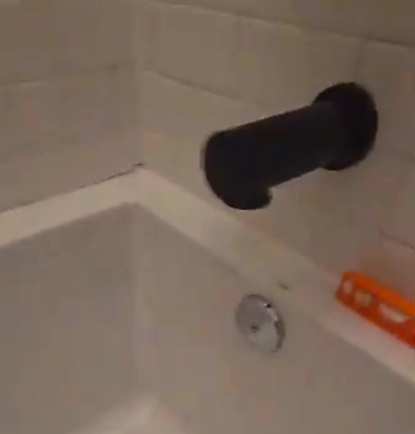 old unleveled bathtub with crack forming from tiled wall