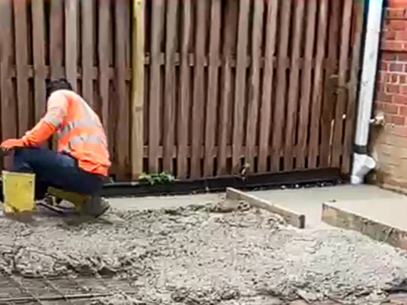 Contractor placing concrete over a reinforced rebar grid during construction of the new stamped concrete patio.