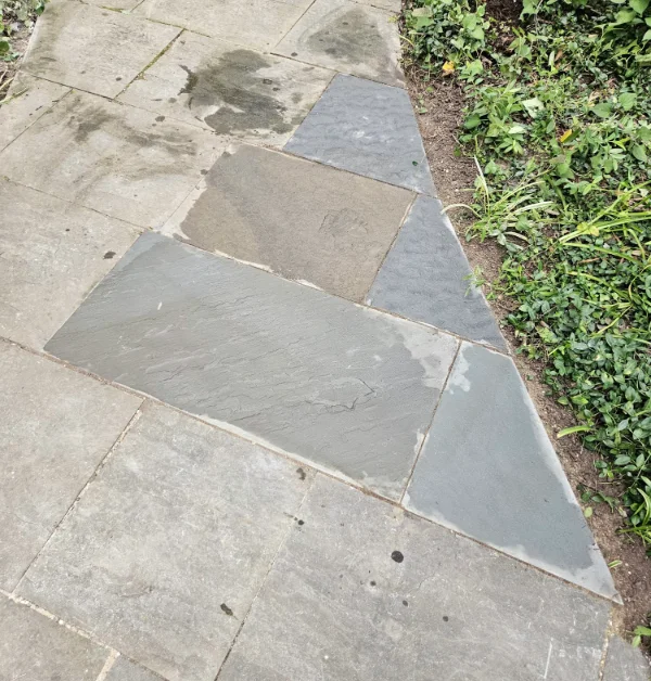 A close-up view of the restored flagstone walkway featuring newly cut, multi-toned gray and tan flagstone pieces seamlessly fitted and leveled with the existing stone path.